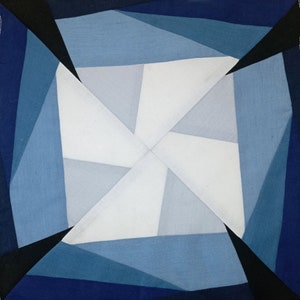 Könnte beinhalten: Ein geometrischer Quiltblock mit einer weißen Mitte und blauen und schwarzen Dreiecken, die nach außen strahlen.