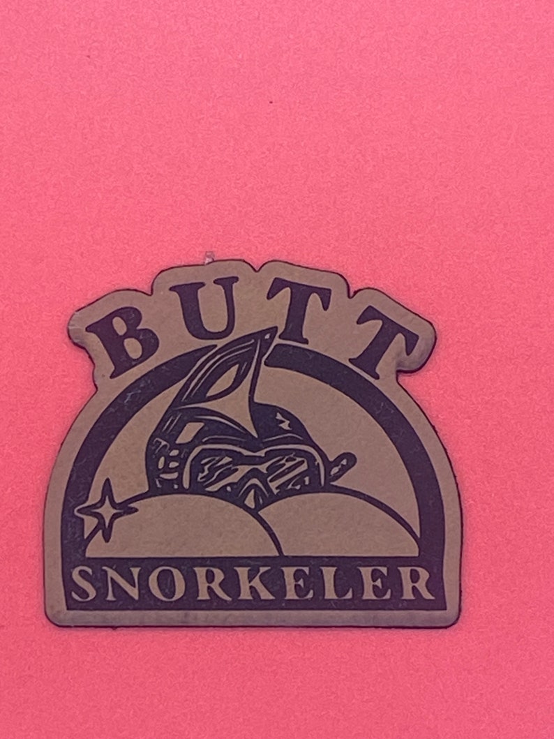 Pu&ograve; includere: Un adesivo marrone e nero con il testo "BUTT SNORKELER" in un cerchio nero. L'adesivo presenta un'illustrazione di cartone animato di una persona che indossa uno snorkel e degli occhiali da sub, con il suo sedere rivolto allo spettatore.