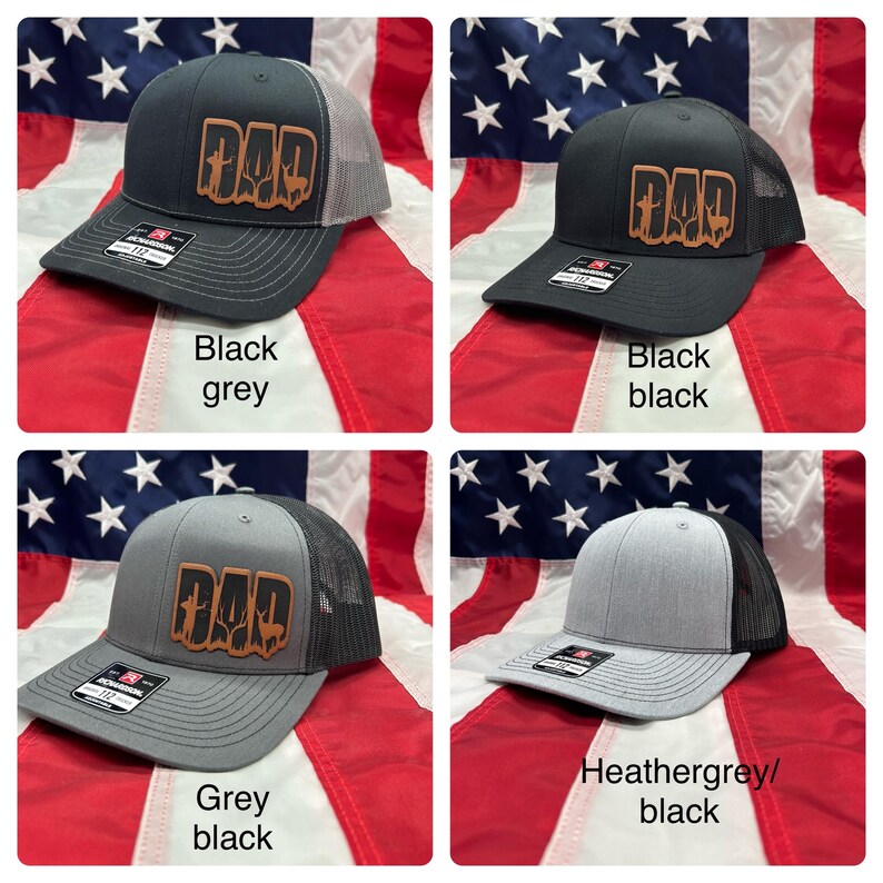 May include: Four different color variations of a black mesh trucker hat with a brown leather patch that says "DAD" with a deer silhouette inside the letters. The hats are displayed on a red, white, and blue American flag background.