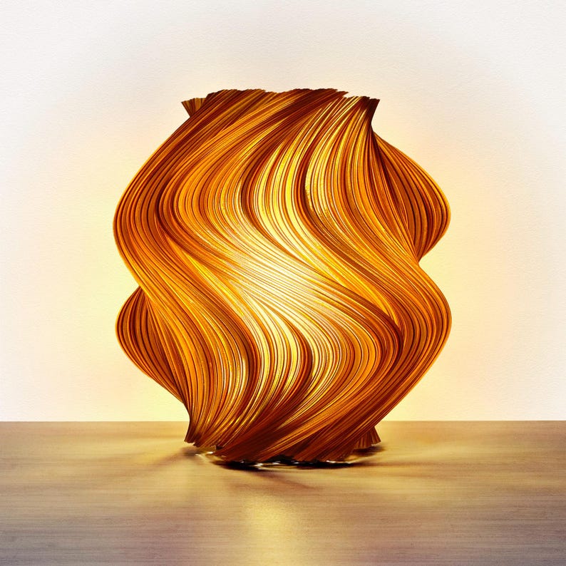 Lámpara decorativa con un diseño único y ondulado. La lámpara está hecha de finas tiras curvas de un material marrón dorado cálido, creando una apariencia texturizada en forma de ola. La fuente de luz interna emite un brillo suave y acogedor.