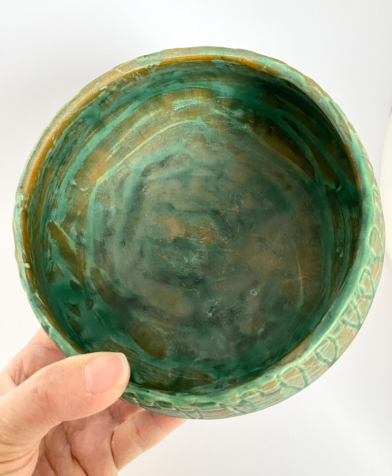 Może przedstawiać: Zielona i brązowa ceramiczna miska z fakturowanym zewnętrzem. Miska ma szeroki, okrągły kształt i gładkie wnętrze.