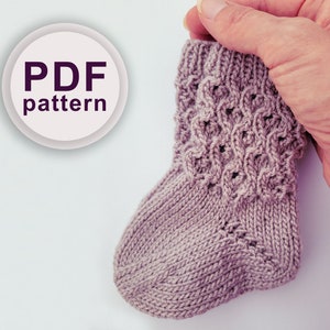 May include: A PDF pattern for knitting a pair of baby socks. The socks are a light purple colour and have a delicate cable knit pattern.