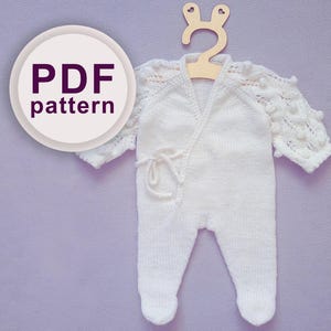 May include: White knitted baby romper with a wrap-style fastening and a decorative knot. The romper has a delicate lace pattern on the sleeves and a pom-pom trim. The image includes the text "PDF pattern".