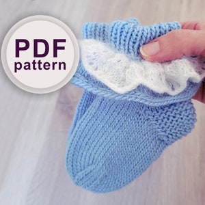 Può includere: Uno schema PDF per lavorare a maglia delle scarpine per neonati con un bordo in pizzo bianco. Le scarpine sono di colore azzurro chiaro e il pizzo è bianco.