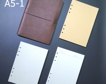 May include: Four different types of A5-1 refillable notebooks. A brown leather bound notebook, a kraft paper notebook, a notebook with a grid pattern, and a notebook with lined paper. The notebooks are all punched with holes for a binder.