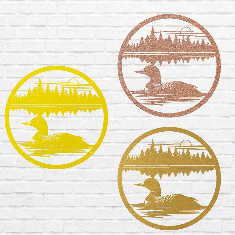 May include: Three round metal wall art pieces in gold, rose gold, and yellow. Each features a loon swimming on water, with a forest and sun design. The art is set within a circular frame, perfect for nature-themed decor.
