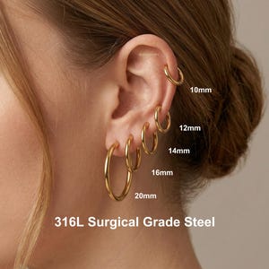 Gold 316L stainless steel stackable hoop earrings worn on ear, showing multiple sizes 10mm to 20mm for lobe and cartilage piercings, minimalist everyday jewelry.
