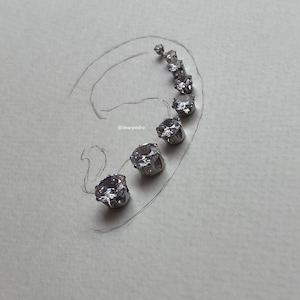 Cubic zirconia stud earrings in sizes 3mm to 10mm arranged on a hand-drawn ear outline, crafted with hypoallergenic 316L surgical steel, showcasing their brilliant diamond-like sparkle