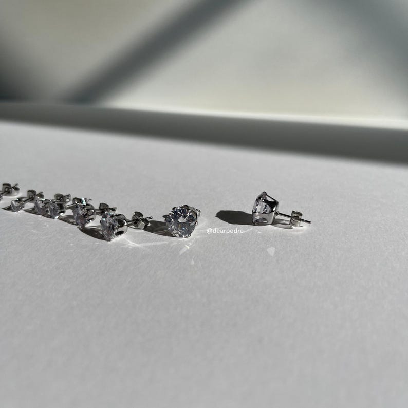 Elegant cubic zirconia stud earrings in various sizes, crafted from 316L surgical steel with a brilliant diamond-like sparkle; perfect for sensitive ears and versatile for any occasion