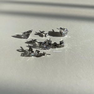 Assorted cubic zirconia stud earrings in sizes 3mm to 10mm, crafted with hypoallergenic 316L surgical steel, featuring a brilliant diamond-like sparkle under natural light