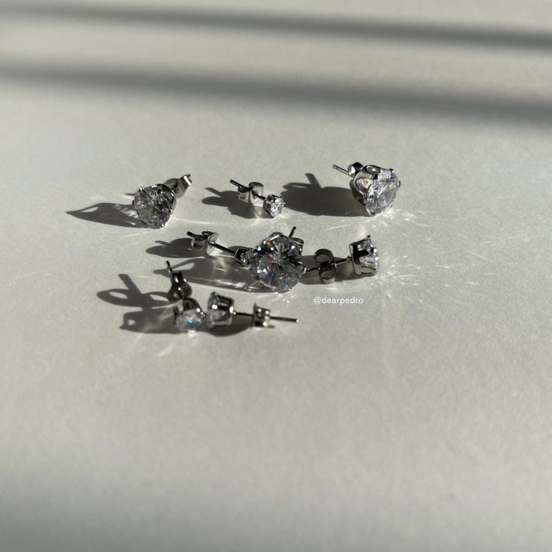 Assorted cubic zirconia stud earrings in sizes 3mm to 10mm, crafted with hypoallergenic 316L surgical steel, featuring a brilliant diamond-like sparkle under natural light