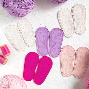 May include: A set of ten colorful fabric patches with various animal designs. The patches are shaped like slippers and have a white background with black outlines. The animals include a cat, a dog, a bear, a fox, a rabbit, a bird, a fish, a turtle, a butterfly, and a ladybug.