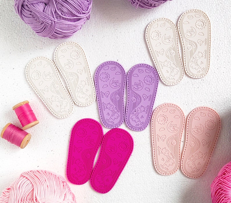 May include: A set of ten colorful fabric patches with various animal designs. The patches are shaped like slippers and have a white background with black outlines. The animals include a cat, a dog, a bear, a fox, a rabbit, a bird, a fish, a turtle, a butterfly, and a ladybug.
