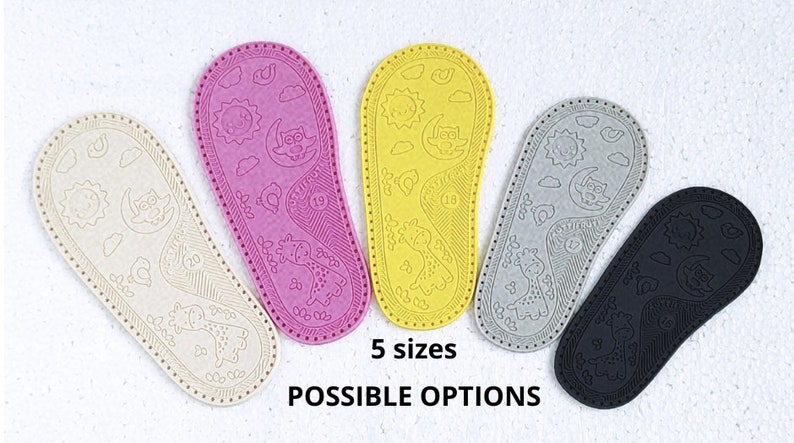May include: Five pairs of baby shoe soles in different colours: beige, pink, yellow, grey, and black. Each sole has a unique design featuring a sun, moon, owl, and giraffe. The text "5 sizes" and "POSSIBLE OPTIONS" is printed below the soles.