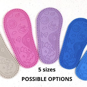 May include: Five pairs of baby shoe soles in different colours: grey, pink, purple, blue, and light blue. Each sole has a giraffe, sun, moon, and owl design. The text "5 sizes" and "POSSIBLE OPTIONS" is printed below the soles.