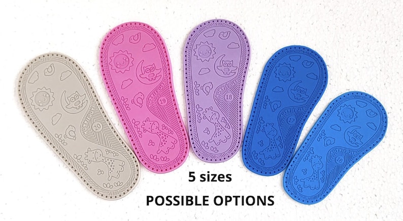 May include: Five pairs of baby shoe soles in different colours: grey, pink, purple, blue, and light blue. Each sole has a giraffe, sun, moon, and owl design. The text "5 sizes" and "POSSIBLE OPTIONS" is printed below the soles.