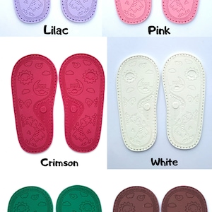 May include: Six pairs of baby shoe soles in different colors: lilac, pink, crimson, white, green, and maroon. Each sole has a design of a sun, moon, owl, and giraffe. The soles are all size 18.
