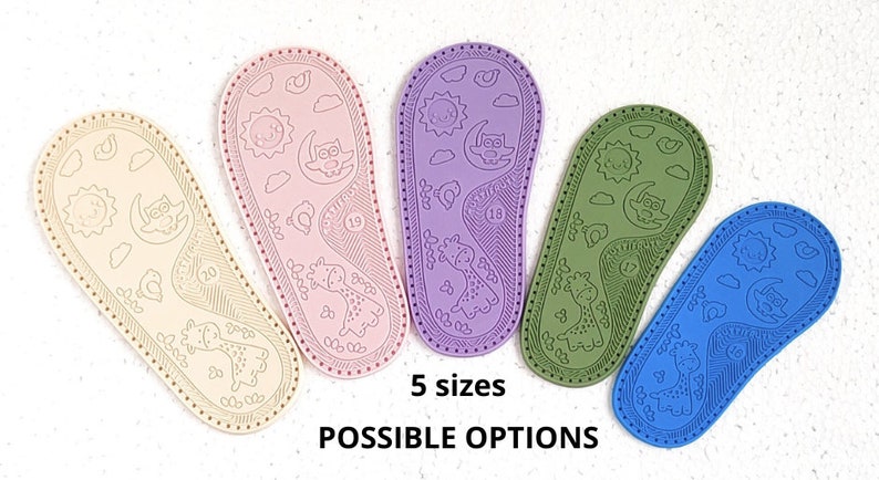 May include: Five pairs of baby shoe soles in different colours: beige, pink, purple, green, and blue. Each sole has a design of a sun, moon, owl, and giraffe. The text "5 sizes" and "POSSIBLE OPTIONS" is printed below the soles.