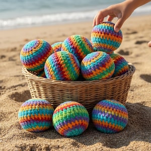 Könnte beinhalten: Ein geflochtener Weidenkorb gefüllt mit mehreren runden, gehäkelten Bällen in einem lebendigen Regenbogen-Streifenmuster. Die Bälle haben eine sichtbare Maschenstruktur und zeigen horizontale Streifen in Blau, Grün, Gelb, Orange und Rot.