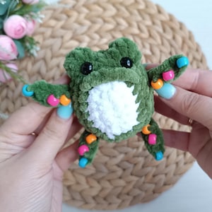 May include: A white ceramic mug with a black handle and the text "But First, Coffee" in a bold, black font. The mug is set against a blurred background, suggesting a cosy setting.