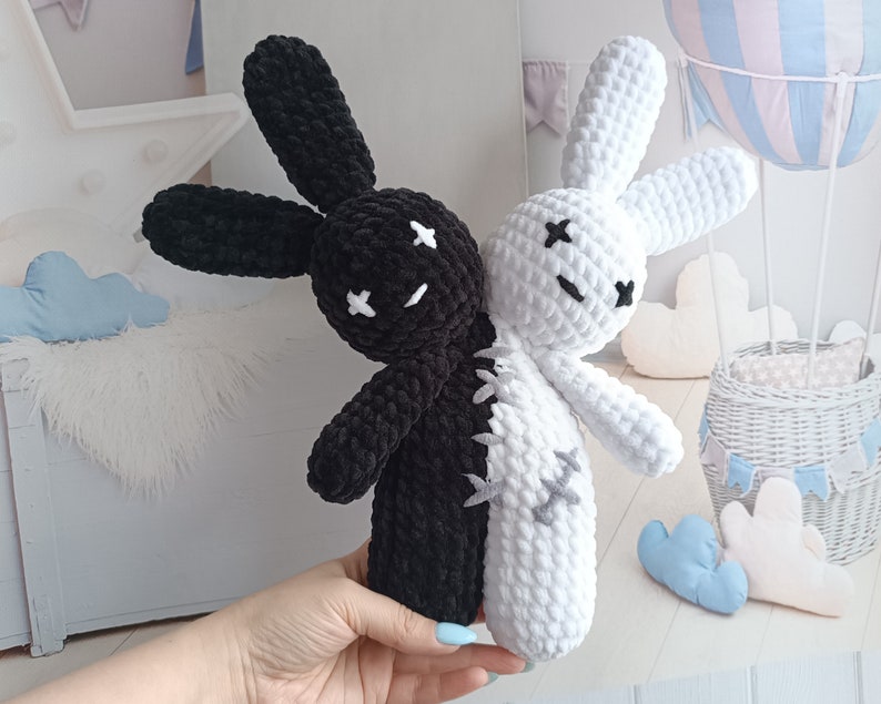 May include: A black and white crocheted bunny toy with a stitched-on X for eyes. The bunny is split down the middle, with one side black and the other white.