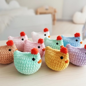 May include: A collection of handmade crochet chicken toys in various pastel colors, including pink, blue, yellow, and green. Each chicken has a red comb, orange beak, and black eyes. These soft toys are suitable for children.