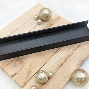 May include: Black plastic tray with a textured surface, resting on a wooden surface. The tray is surrounded by gold glitter balls.