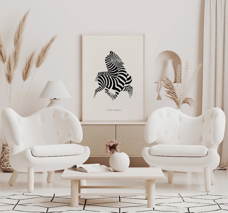 K&ouml;nnte beinhalten: Ein abstrakter Zebra-Kunstdruck in Schwarzwei&szlig; in einem wei&szlig;en Rahmen, der an einer wei&szlig;en Wand &uuml;ber einem wei&szlig;en Sofa h&auml;ngt. Der Druck ist mit "Victor Vasarely" betitelt.