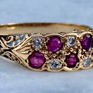 May include: A gold ring featuring a cluster of red rubies and white diamonds set in a floral design.