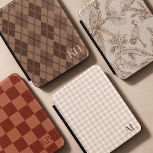 May include: Four rectangular tablet cases with rounded corners. One features a brown argyle pattern with the initials KH, one has a beige tropical print with birds and leopards, one is a rust-colored checkerboard, and one is a beige gingham with AL.
