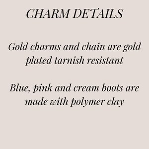 May include: Charm details text explaining that the gold charms and chain are gold plated and tarnish resistant. The blue, pink, and cream boots are made with polymer clay.