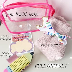 K&ouml;nnte beinhalten: Eine rosa durchsichtige Plastiktasche mit einem goldenen Buchstaben J, eine rosa flauschige Socke mit einem Regenbogenband, ein Haftnotizblock mit einer Wolke und dem Text "with appreciation to you" und eine Bleistifthalterung.