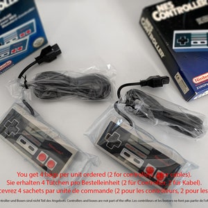 Op de afbeelding: Twee grijze en zwarte Nintendo NES-controllers met rode knoppen, verpakt in doorzichtige plastic zakken met zwarte snoeren. De controllers liggen op een wit oppervlak. De tekst op de verpakking luidt: "You get 4 bags per unit ordered (2 for controllers, 2 for cables). Sie erhalten 4 Tütchen pro Bestelleinheit (2 für Controller, 2 für Kabel). Vous recevrez 4 sachets par unité de commande (2 pour les controleurs, 2 pour les câbles). Controller und Boxen sind nicht Teil des Angebots. Controllers and boxes are not part of the offer. Les contrôleurs et les boitiers ne font pas partie de l'offre"