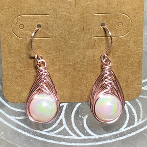White plastic bead with a rainbow luster wrapped in rose colored copper wire- Herringbone style