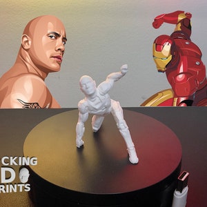Puede incluir: Una figura de acci&oacute;n blanca impresa en 3D en posici&oacute;n agachada, sobre un fondo con ilustraciones de Dwayne Johnson e Iron Man. La figura est&aacute; sobre una plataforma giratoria negra. El texto "ROCKING 3D PRINTS" es visible.