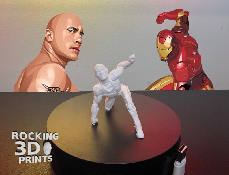 Puede incluir: Una figura de acci&oacute;n blanca impresa en 3D en posici&oacute;n agachada, sobre un fondo con ilustraciones de Dwayne Johnson e Iron Man. La figura est&aacute; sobre una plataforma giratoria negra. El texto "ROCKING 3D PRINTS" es visible.