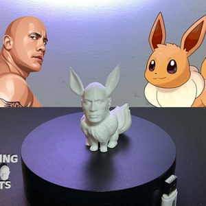 Może przedstawiać: Biała figurka Pokemon z twarzą Dwayne'a "The Rock" Johnsona, wydrukowana w 3D. Figurka stoi na czarnej, okrągłej podstawie. W lewym dolnym rogu zdjęcia widoczny jest napis "ROCKING 3D PRINTS".