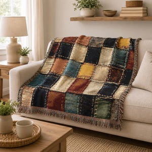 Puede incluir: Una manta tejida con un diseño de patchwork multicolor con bloques rectangulares en tonos azul marino, amarillo mostaza, rojo intenso, verde bosque y beige, terminada con un fleco decorativo a lo largo de los bordes de la tela.