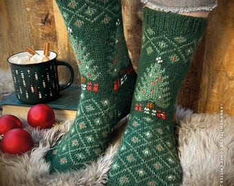 May include: A pair of green knitted socks with a Christmas tree pattern. The socks are worn on a person's feet and are resting on a fuzzy brown surface.