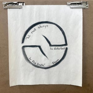 May include: Hand-drawn artwork on textured paper, held by metal clips. The artwork features a dark gray circular design with the quote "We must always be disturbed by the truth." and the name "Dogen".