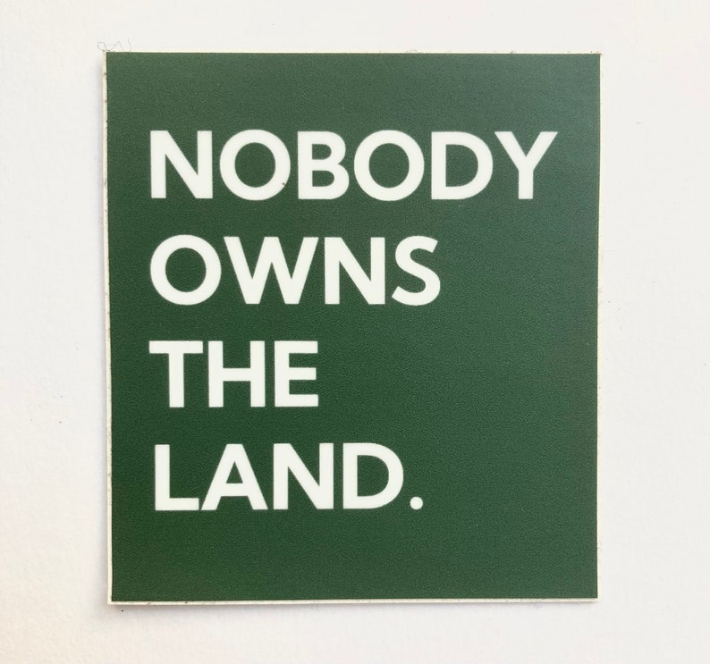 May include: A dark green square sticker with white text that reads "NOBODY OWNS THE LAND."