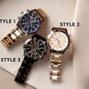 a couple of watches sitting on top of a white cloth