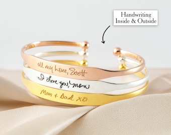 May include: A set of three gold, silver, and rose gold bangle bracelets with handwritten messages engraved on the inside and outside. The messages include "All my love, Scott", "I love you, Mom", and "Mom & Dad XO".