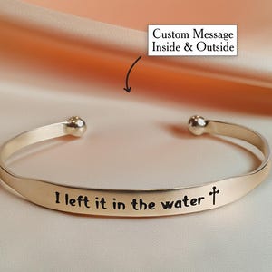 May include: Gold bangle bracelet with a custom inscription that reads "I left it in the water +"