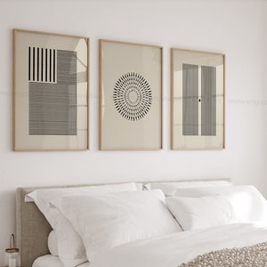 Può includere: Tre stampe geometriche minimaliste in bianco e nero in cornici di legno su una parete bianca sopra un letto con biancheria da letto bianca.