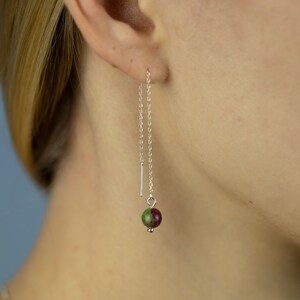 May include: Silver chain earrings with a green and red gemstone bead.