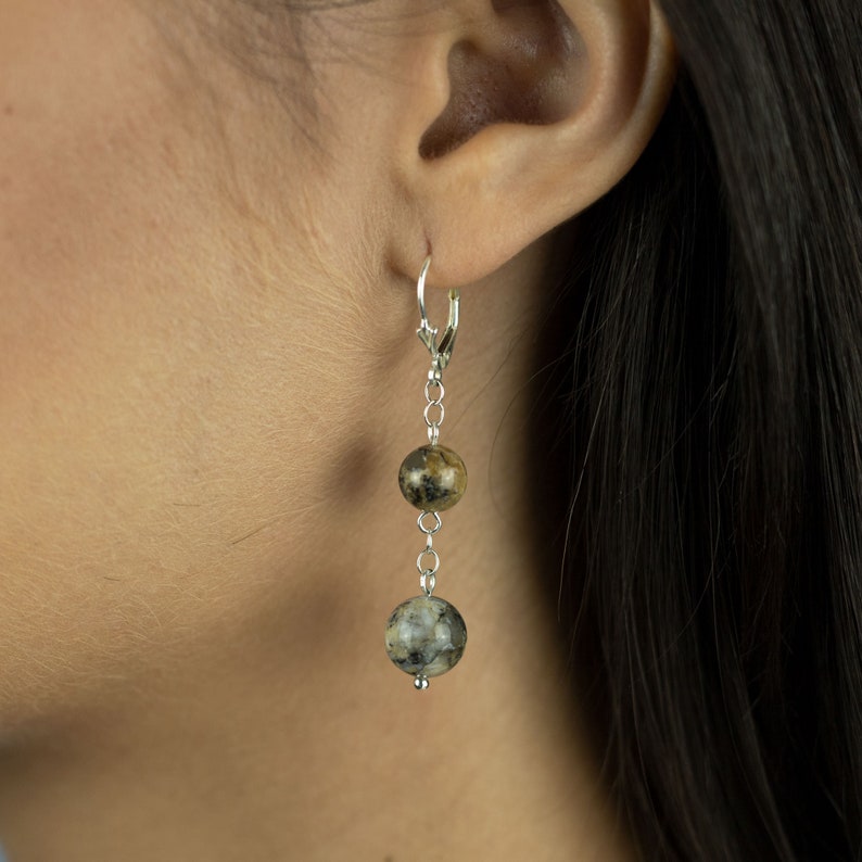 May include: Silver dangle earrings with two round, brown and grey patterned beads.