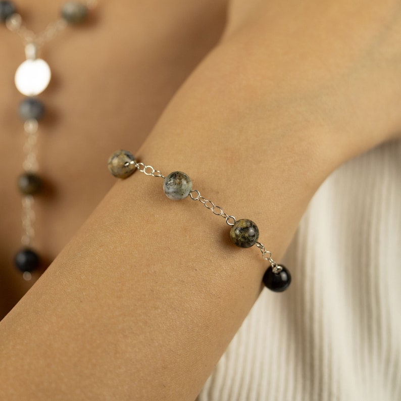 May include: A silver chain bracelet with alternating black and grey-green gemstone beads.