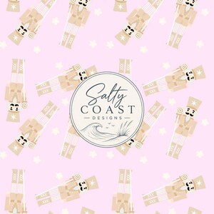 May include: A repeating pattern of beige nutcracker figures on a light pink background with small white flower shapes. In the centre, a circular logo features the text Salty Coast Designs above a line drawing of a wave and tall grass.