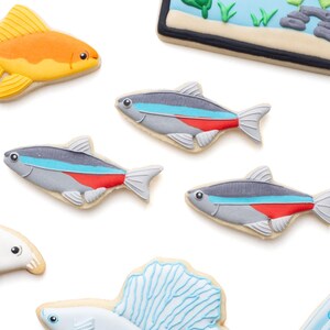 May include: Assortment of fish-shaped cookies, including a goldfish, several neon tetras, and a betta fish, all decorated with colorful icing. There is also a cookie shaped like an aquarium.